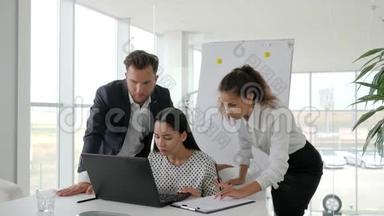 愉快地拥抱办公场所的合作者，在笔记本电脑上成功的商业交易，快乐的商业伙伴